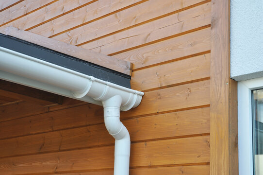 Rain gutter system with downspout installation waterproofing on wooden wall