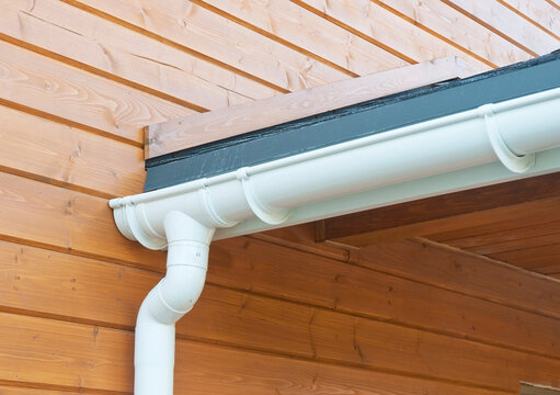 Rain gutter system with downspout installation waterproofing on wooden wall