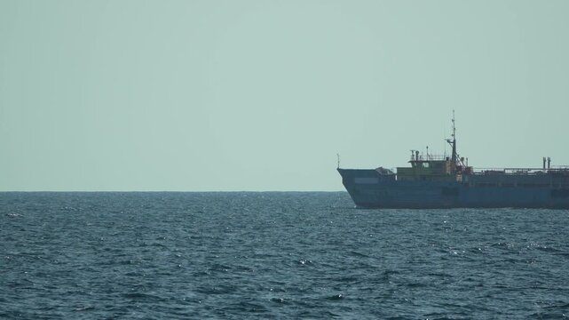 Cargo ship, ocean, vessel, large industrial tanker moving slowly across the calm blue sea