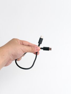 Person hand holding black USB type C charging and data cable isolated on white background
