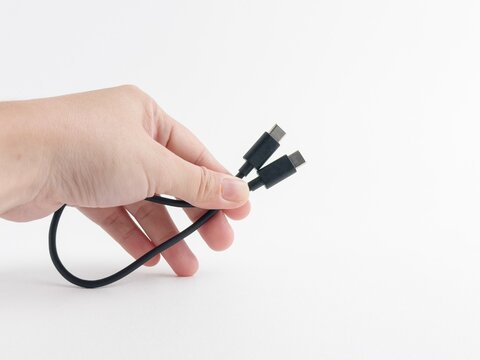 Person hand holding black USB type C charging and data cable isolated on white background