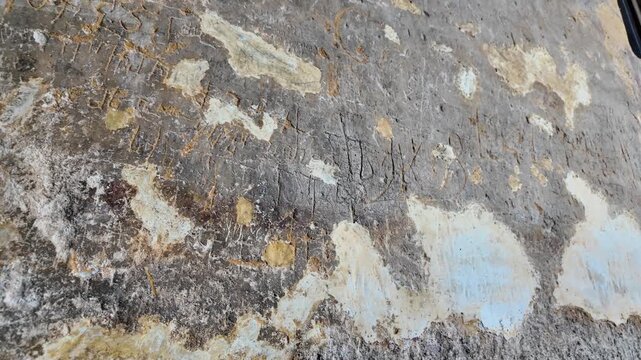 An old stone wall with ancient runic carvings is historical relic of Viking Age. Norwegian script and symbols engraved on weathered surface of the rock tell stories of the past civilization of Vardzia