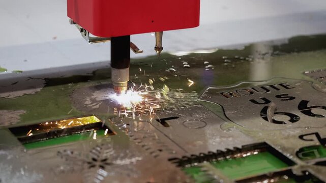 Modern CNC laser cutter carves out pattern on stainless sheet in manufacturing workshop closeup. Lathe machine tool cuts out metal at industrial exhibition