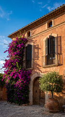 Obraz premium Southern European villa facade, terracotta walls, arched openings, wrought iron shutters, vivid bougainvillea, warm afternoon sunlight, no people