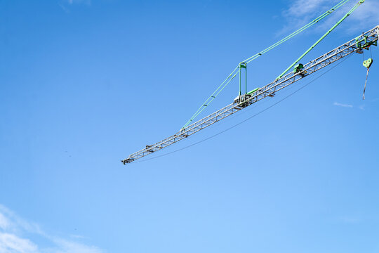 Construction crane against blue sky. Modern engineering, development and building construction projects in urban city area. Horizontal photo of engineering, transport and heavy lifting at industrial s