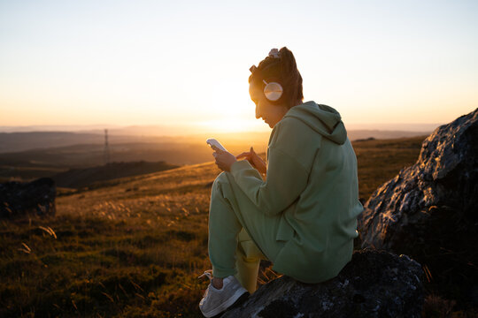Young white woman listening to music on smartphone outdoors