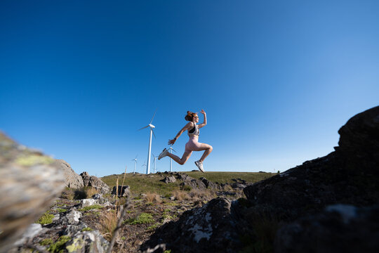 A white woman jumping energetically outdoors