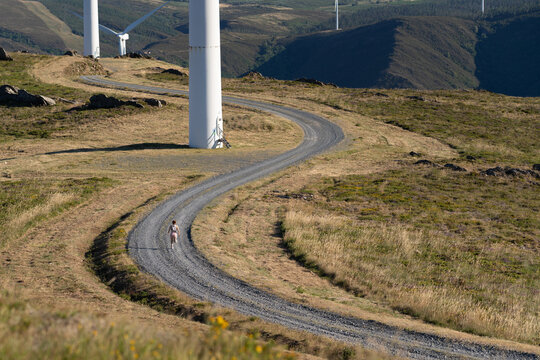 White Woman running on gravel road by wind turbines in Galicia Spain