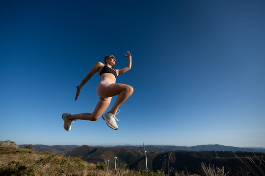 A white woman jumps energetically during an outdoor workout in Galicia