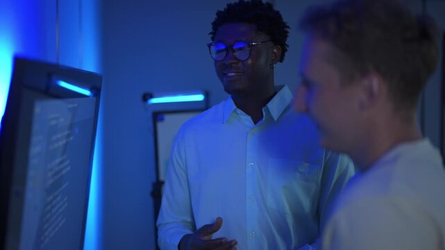 Two diverse programmers working together on a coding project in a modern office.