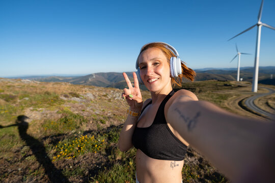 Young white woman takes a selfie at a wind farm in Galicia, Spain