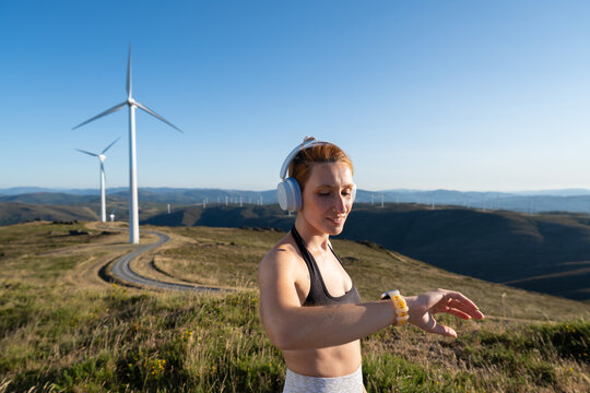 A white woman checks her fitness tracker during outdoor workout