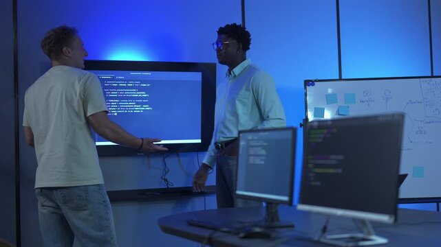 Two diverse programmers working together on a coding project in a modern office.