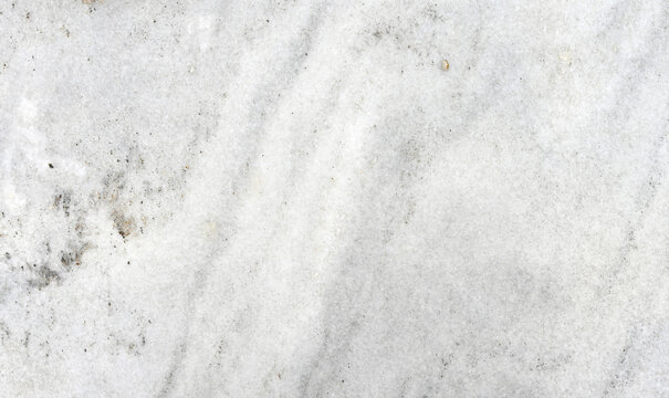Horizontal close up view of an unpolished white granite slab with gray veins, gray and white banding, gold and silvery gray mineral clusters, and natural grainy texture