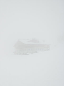 A building on a ski piste in Austria in a thick layer of mist fog.
