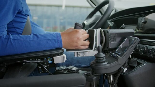 Close-up of a powered wheelchair user driving an adapted van with hand controls and assistive technology for independent mobility.