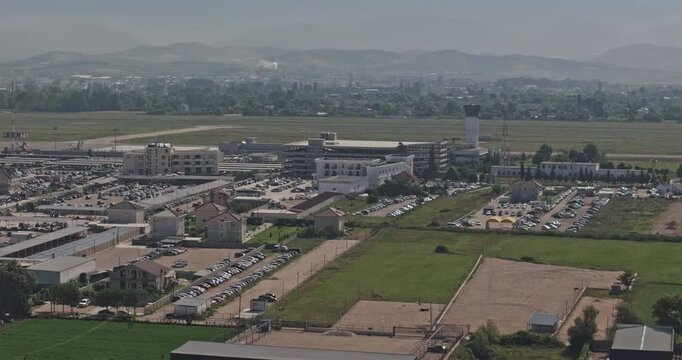 Tirane Albania Aerial v6 telephoto low flyover revealing Tirana International Airport runway, terminal district and vehicle lots beyond Rinas farmland - Shot with Mavic 3 Pro Cine - July 10th 2024