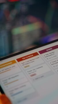 Close-up of developer hands holding digital tablet displaying agile project management board with completed tasks, code review tickets
