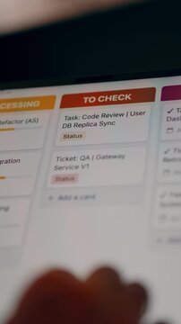 Agile IT project task board ticket to check quality assurance interface display. Close-up of developer holding tablet showing project management workflow dashboard with code review tasks