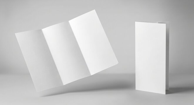 Two blank white matte tri-fold brochures floating and standing on a smooth light gray backdrop with soft natural shadows.