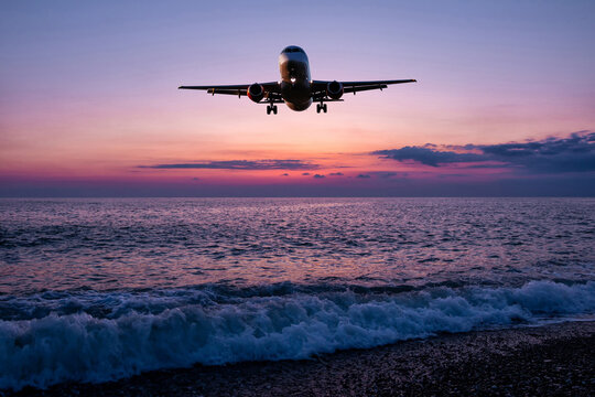 Passenger aircraft landing over the sea against the backdrop of scenic sunrise sky