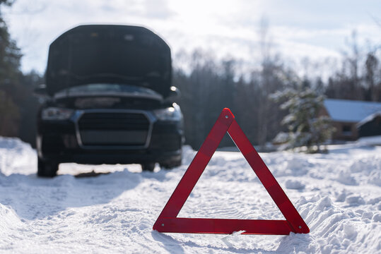 Emergency car breakdown warning triangle on snowy winter road