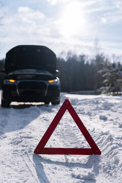 Emergency car breakdown warning triangle on snowy winter road
