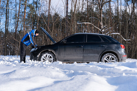 Driver inspect broken car on snowy winter roadside