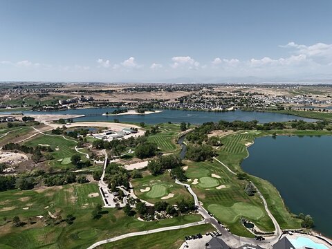 Aerial view of Pelican Lakes Point golf course featuring lush green fairways, winding paths, and serene water bodies surrounded by residential neighborhoods in Windsor, Colorado, United States.
