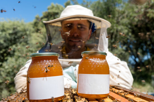 Beekeeper with honey jars and Apis mellifera iberiensis