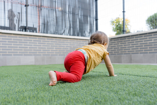 Baby crawl on artificial grass in urban playground