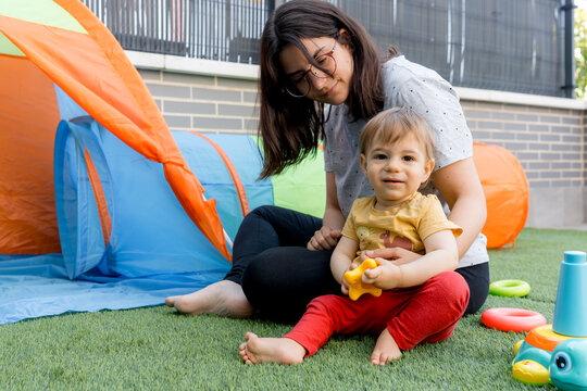 Mother and baby play with toy beside colorful play tent