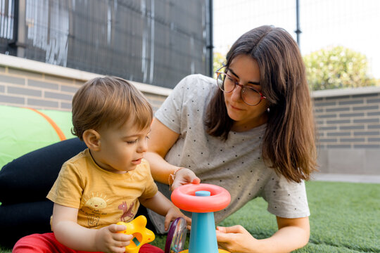 Mother and baby play with toy on artificial grass