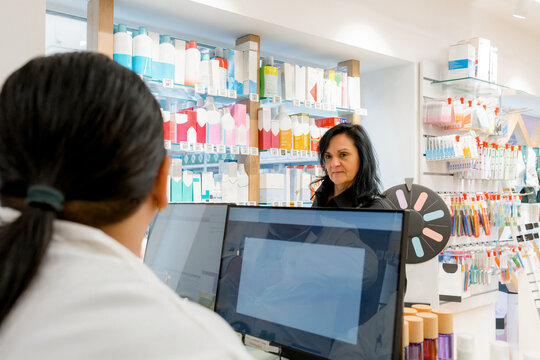 Pharmacist assist customer at medicine counter in pharmacy