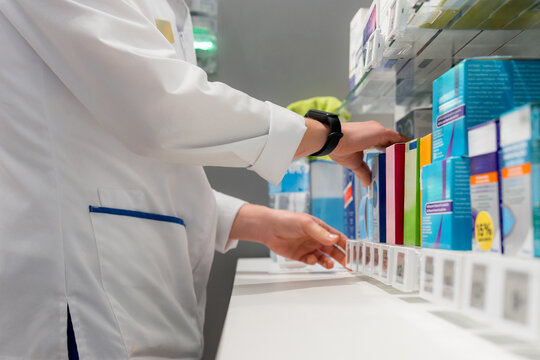 Pharmacist select medicine box from pharmacy shelf