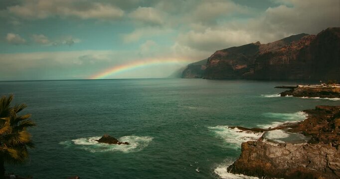 Fading Rainbow Over Coastal Cliffs and Ocean Waters in Tenerife Spain