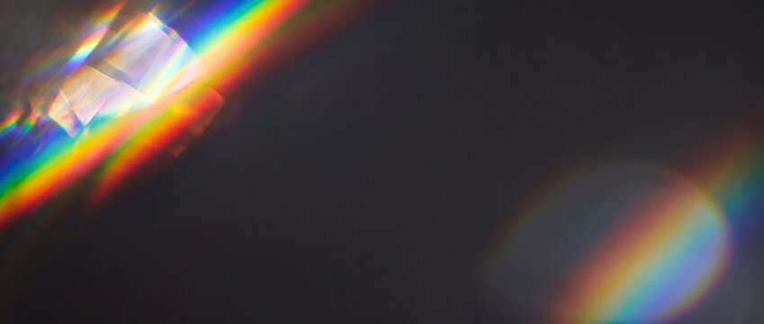 Rainbow light refraction on dark background features vibrant spectral prism flares and subtle bokeh overlays for creative overlay designs, digital backgrounds, and banner covers