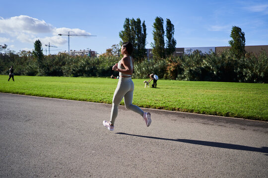 Young african millennial woman running in park on a sunny morning, wearing sportswear and sneakers. She trains with energy and determination, enjoying a healthy active lifestyle outdoors.