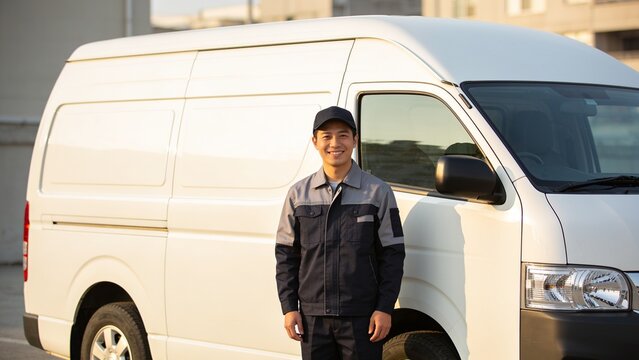 Professional delivery driver standing proudly beside white cargo van in urban business district.