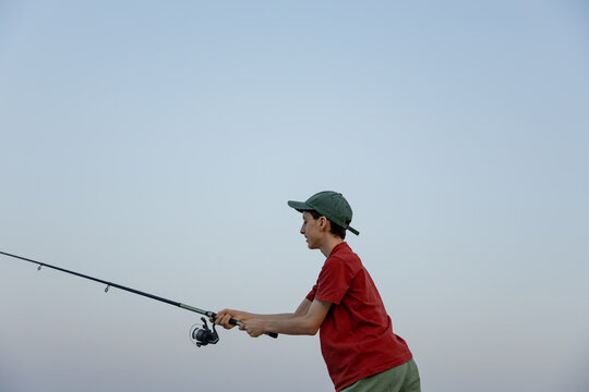 Teenager fish with rod under clear open sky