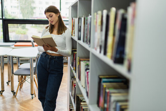 Teenage girl immersed in a book at a modern school library