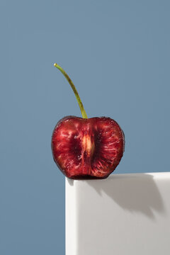 Split Jerte cherry with stem on blue background