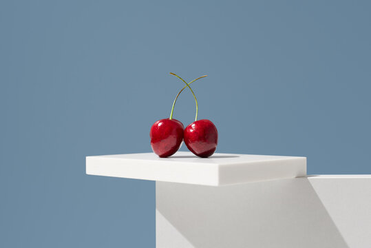 Jerte Picota cherries on white pedestal against blue background