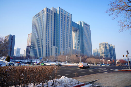 Street scene with cars in motion on road. Winter city life in China. Cars cross an intersection in the city. Tower buildings in urban life. China, Xinjiang, Urumqi, Jan 2, 2026.