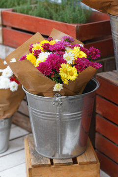 Fresh chrysanthemum bouquet in a rustic metal bucket at an autumn flower market or floral shop. Colorful seasonal flowers create a cozy fall display for home decor, gifts and festive arrangements.