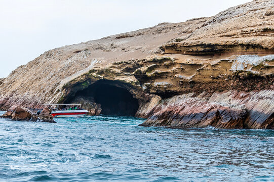 A view of a tourist boat entering a large cave in the Ballestas Islands, Paracas, Peru in the dry season