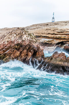 A view from a tourist boat of waves breaking against the Ballestas Islands, Paracas, Peru in the dry season