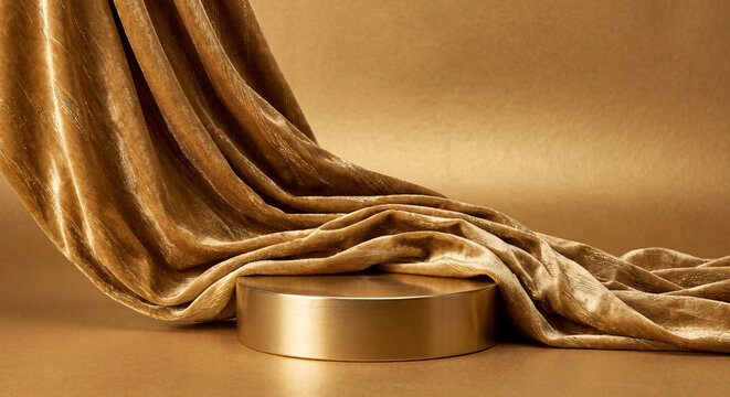 Luxurious golden silk fabric is draped elegantly over a metallic cylindrical podium against a warm background.