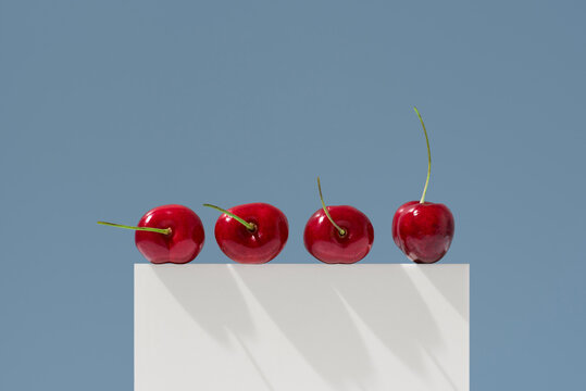 Jerte Picota cherries on white pedestal against blue background