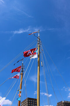 Wooden sailboat masts decorated with colorful nautical flags under a clear blue sky